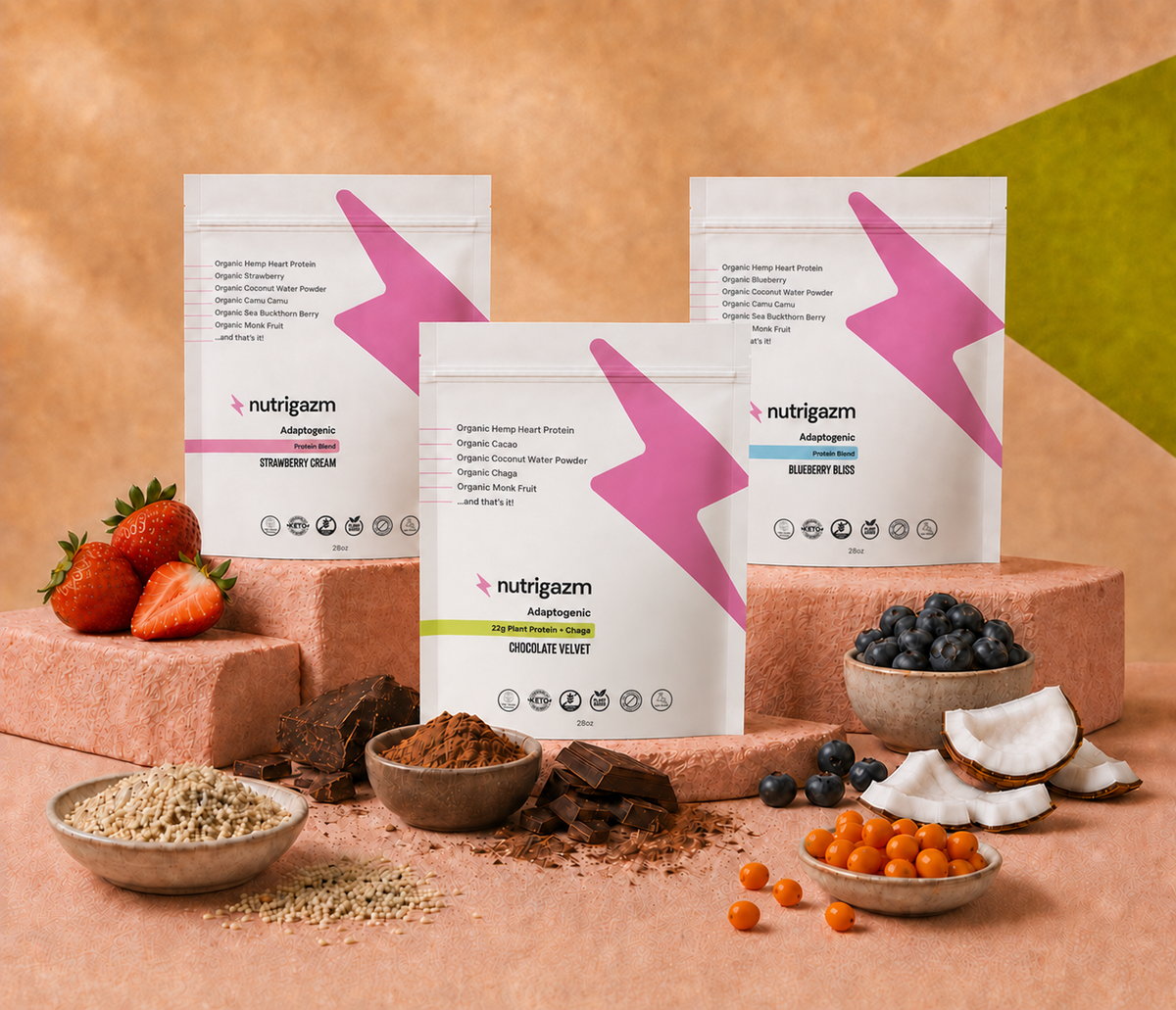 Nutrigazm Strawberry Cream, Blueberry Bliss, and Chocolate Velvet pouches surrounded by strawberries, blueberries, cacao, hemp hearts, coconut, and sea buckthorn.